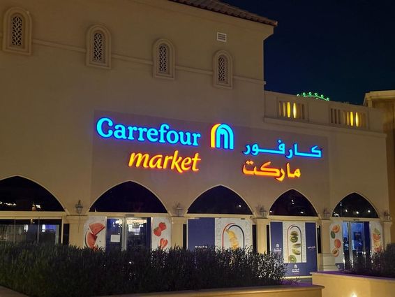 Illuminated logo of Carrefour market with Arabic brand name