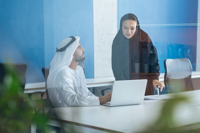 A man and a woman in traditional attire working in a business office in Dubai.