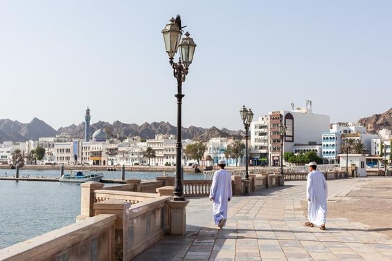 Men in traditional Omani attire along Muscat waterfront.