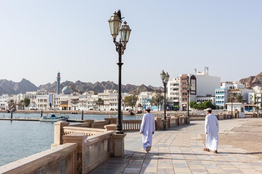 Men in traditional Omani attire along Muscat waterfront.